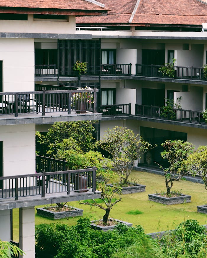 Contemporary multi-story building with lush courtyard and distinctive balconies, showcasing modern architecture.